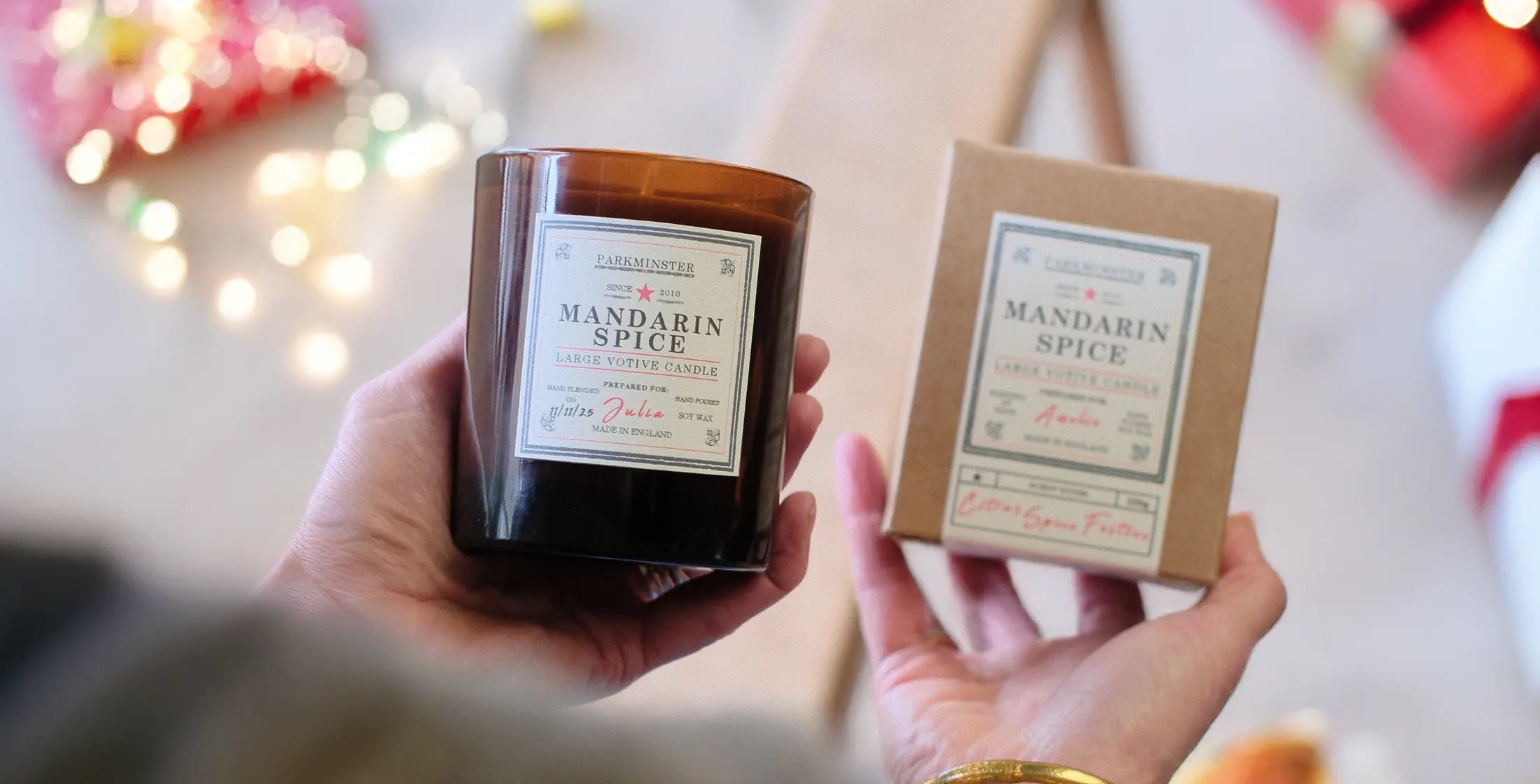 Someone unwrapping a Parkminster Large Votive Candle on Christmas morning, surrounded by presents – a natural, handmade candle that makes the perfect Christmas gift.