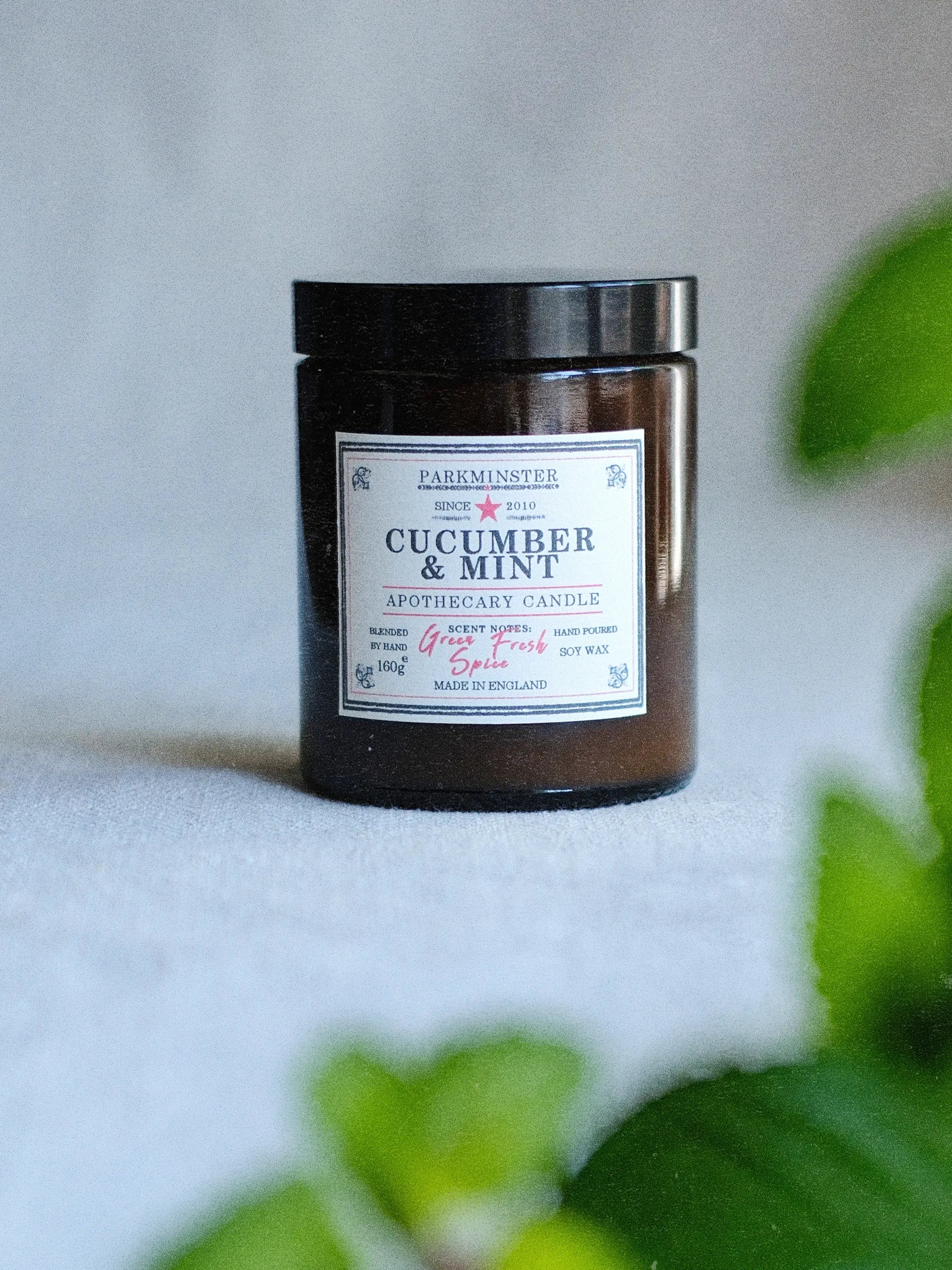 Apothecary-style amber glass candle jar labeled “Cucumber & Mint,” featuring a clean, spa-inspired soy wax candle with a fresh green fragrance profile, designed for a calming and refreshing home atmosphere.