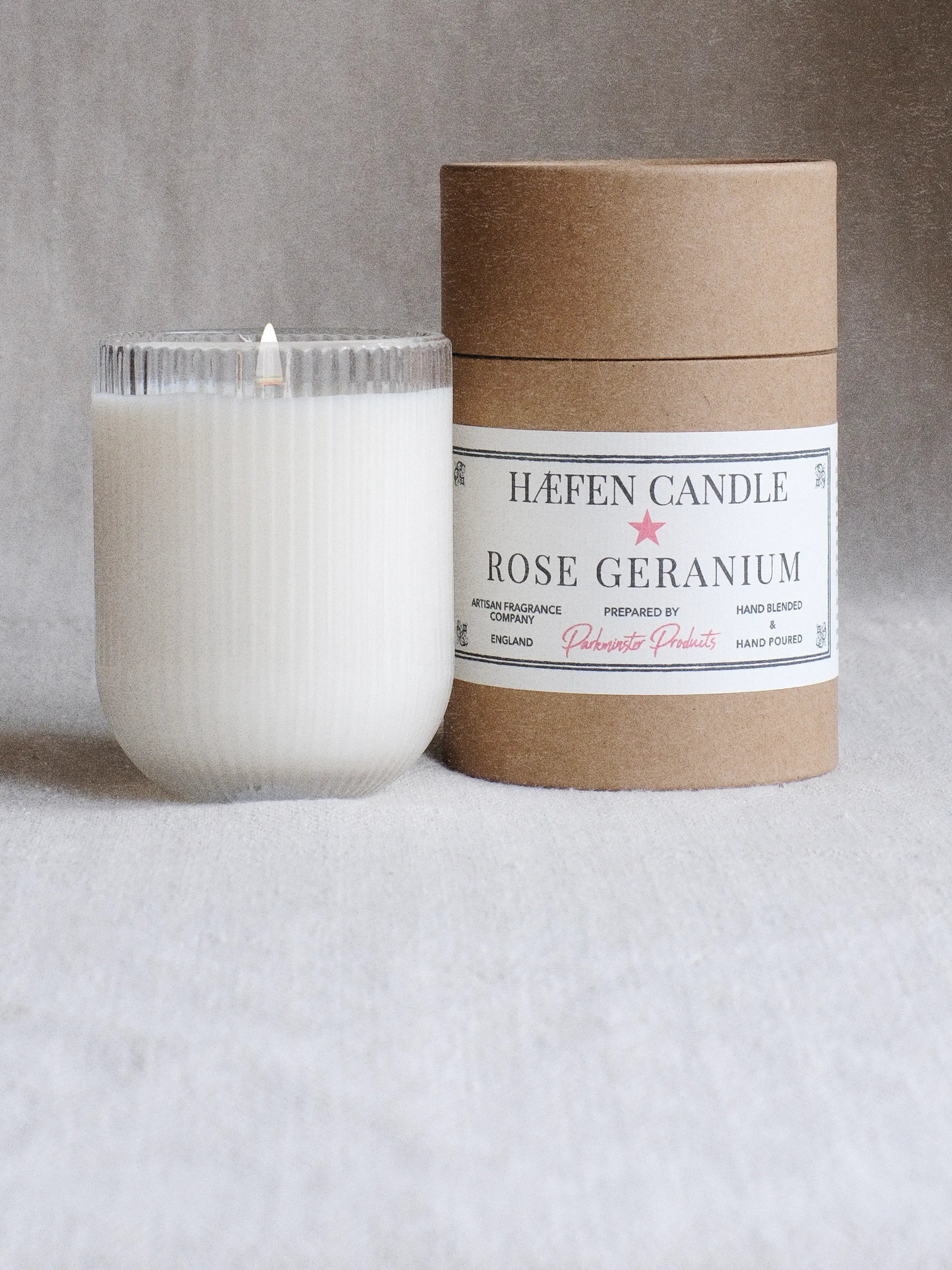 a Parkminster Rose Geranium HÆFEN soy wax candle in ribbed glass with kraft paper tube gift packaging behind – natural floral scented candle made in Cornwall