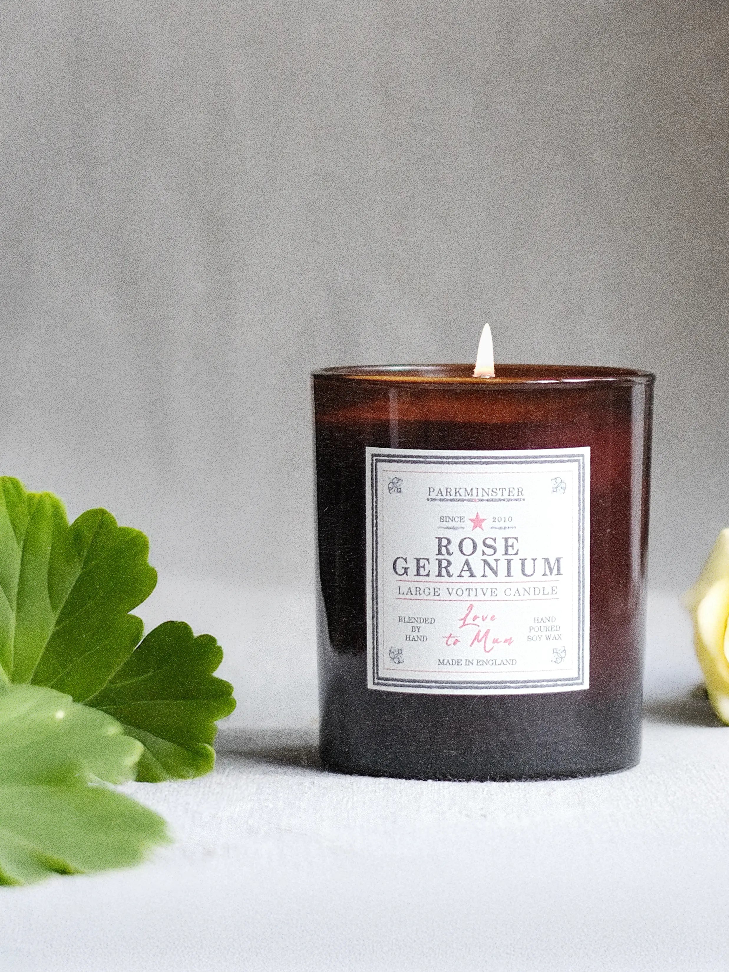 a Natural Rose Geranium soy wax scented candle in an amber jar, perfect as a candle gift or Mother’s Day candle with deeply floral and a botanical fresh herbal fragrance.