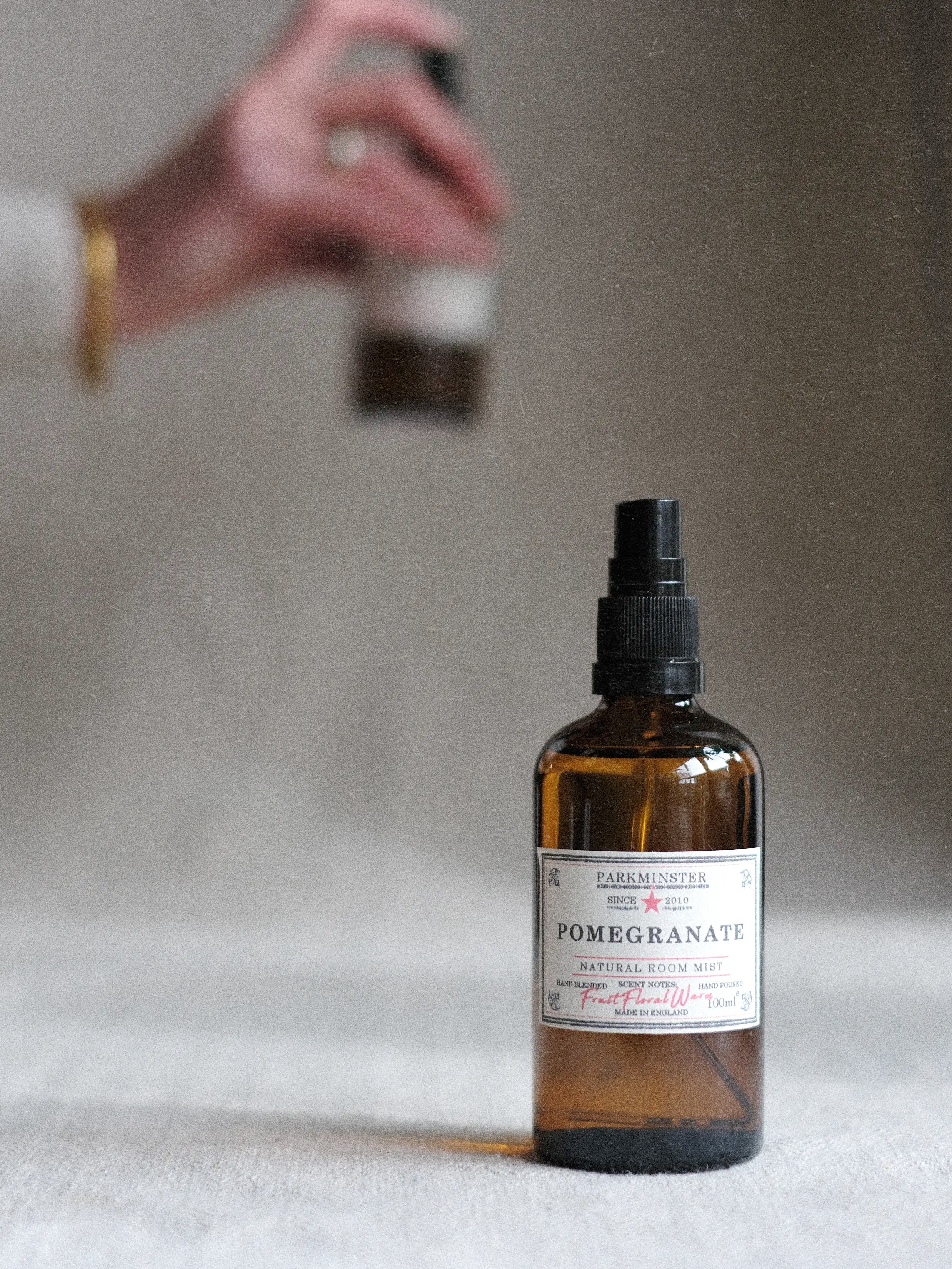 a person spraying a Pomegranate scented room spray made by Parkminster for a refreshingly fruity home fragrance