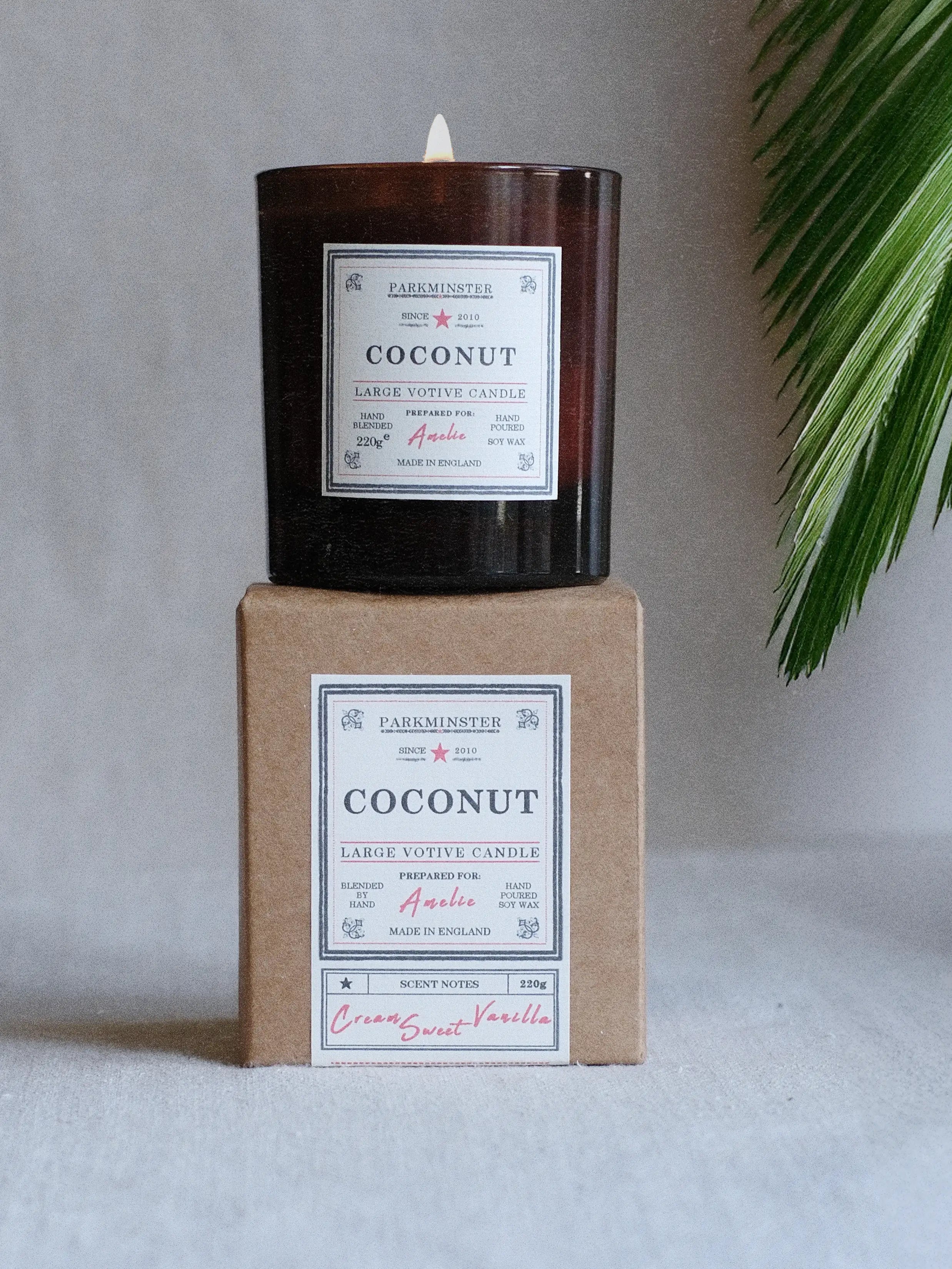 a Parkminster Coconut scented soy candle in large votive glass jar on neutral linen background with palm fronds, evoking a fresh tropical coconut fragrance for calm, natural interiors