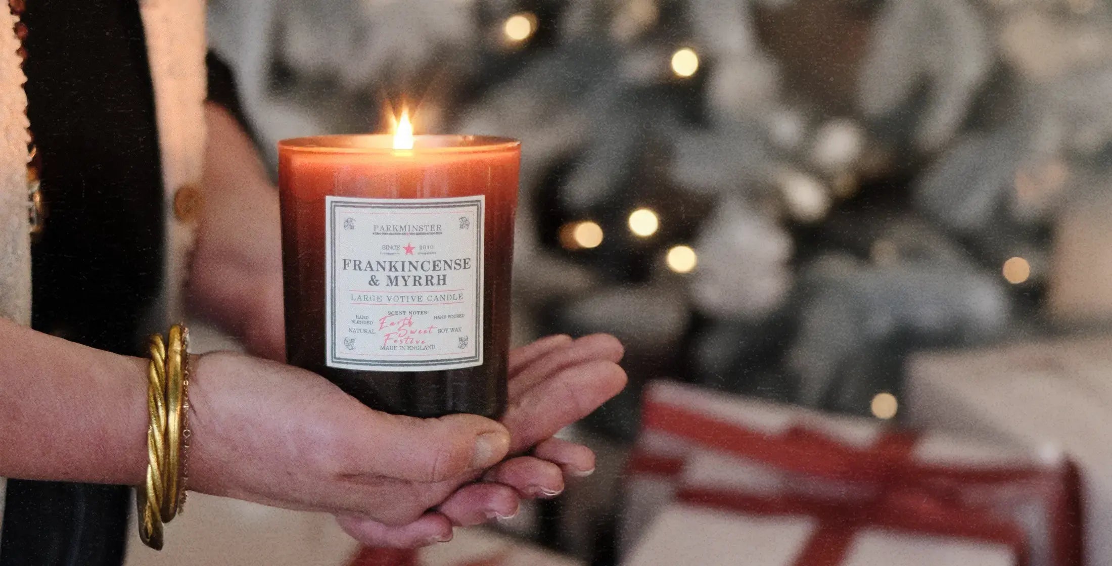 Someone unwrapping and lighting a Parkminster Frankincense & Myrrh Large Votive Candle – a natural Christmas candle and a perfect festive gift for friends, family, or yourself.