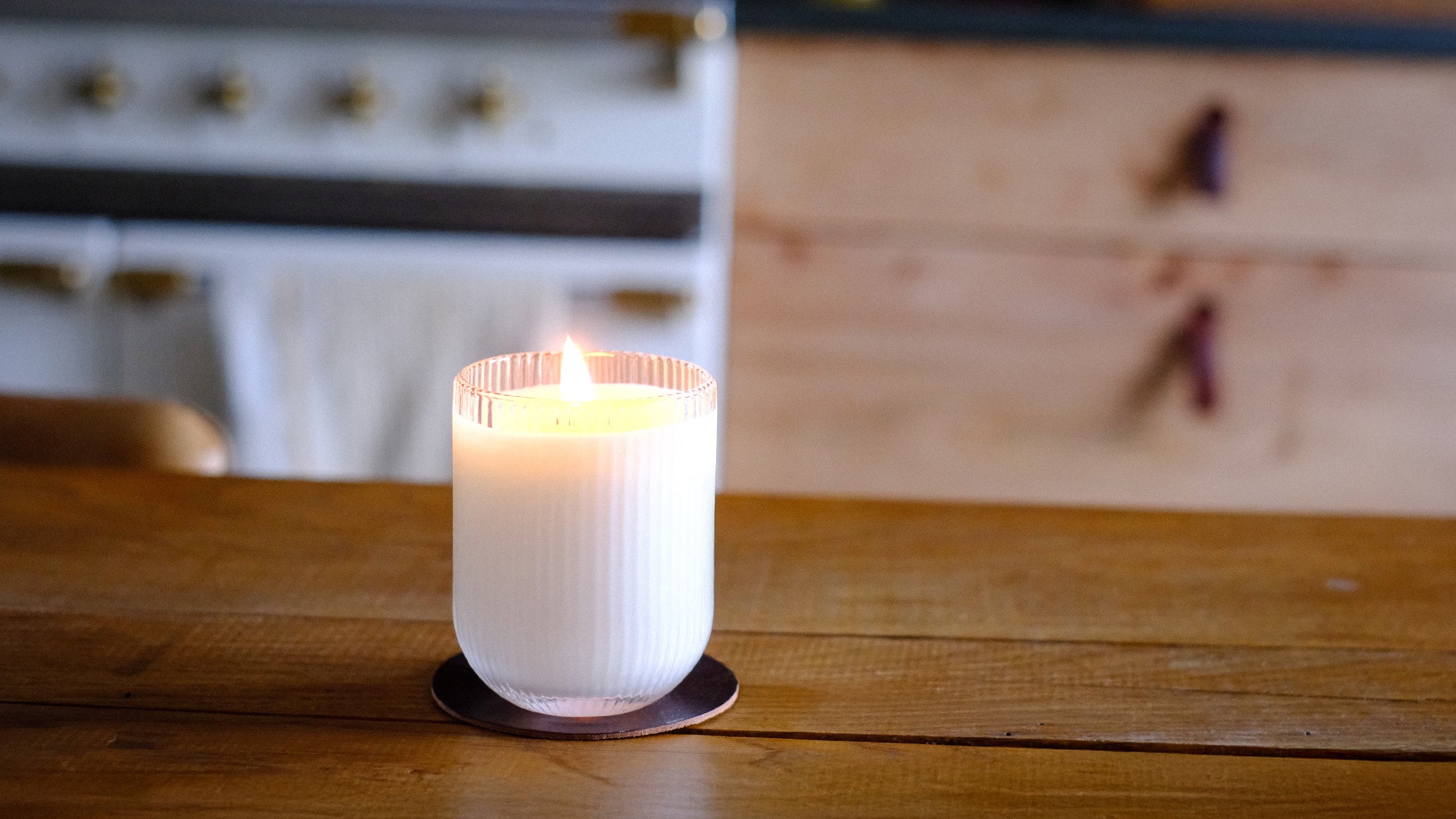 Parkminster Haven Scented Candle burning on a large kitchen table in a prestigious contemporary country house, showcasing natural soy wax and sustainable glamour of Parkminster's Candles