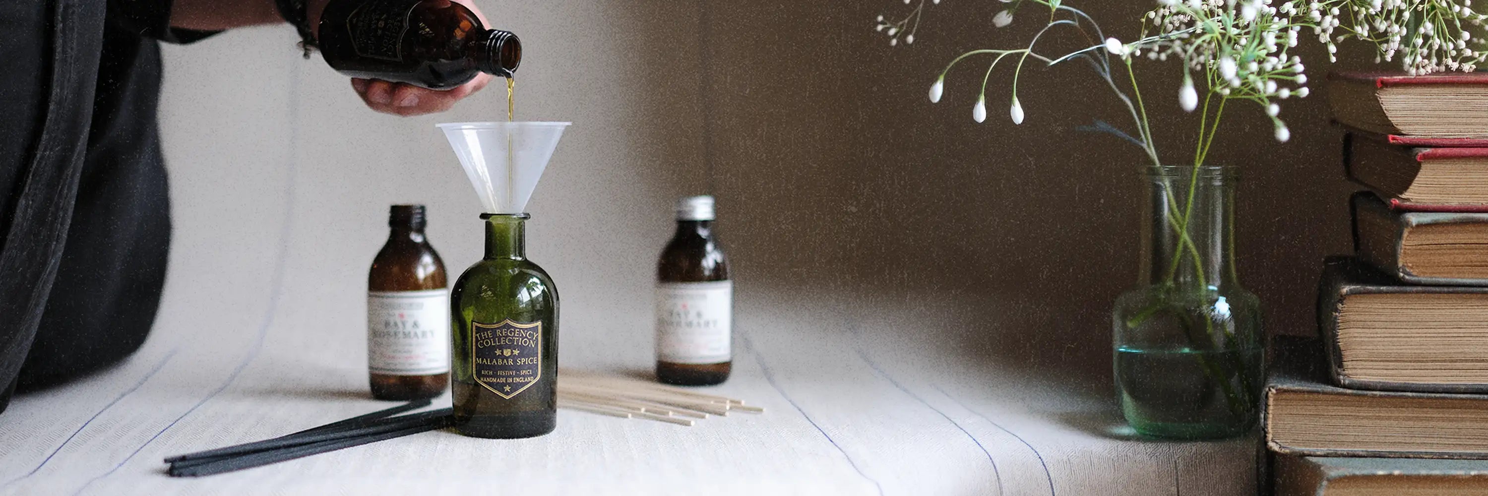 Person refilling a Parkminster Regency Collection reed diffuser using a natural reed diffuser refill bottle with fresh reeds in a natural home setting showing sustainable home fragrance use