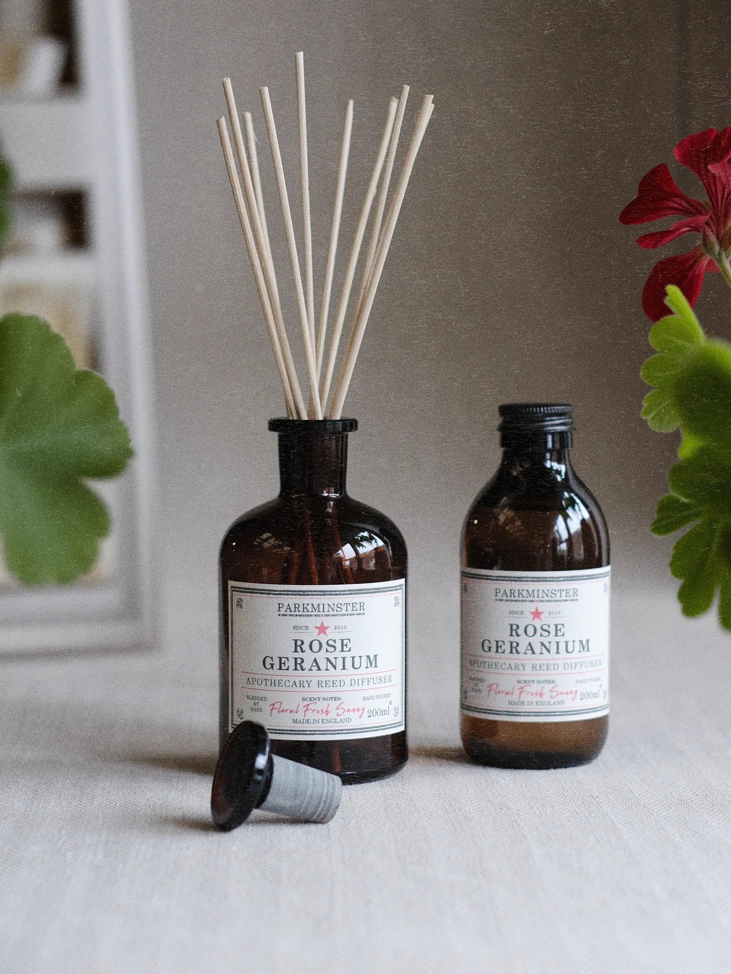 a Parkminster Rose Geranium 200ml Apothecary Reed Diffuser with a fresh floral and positive fragrance, all in an amber brown jar.