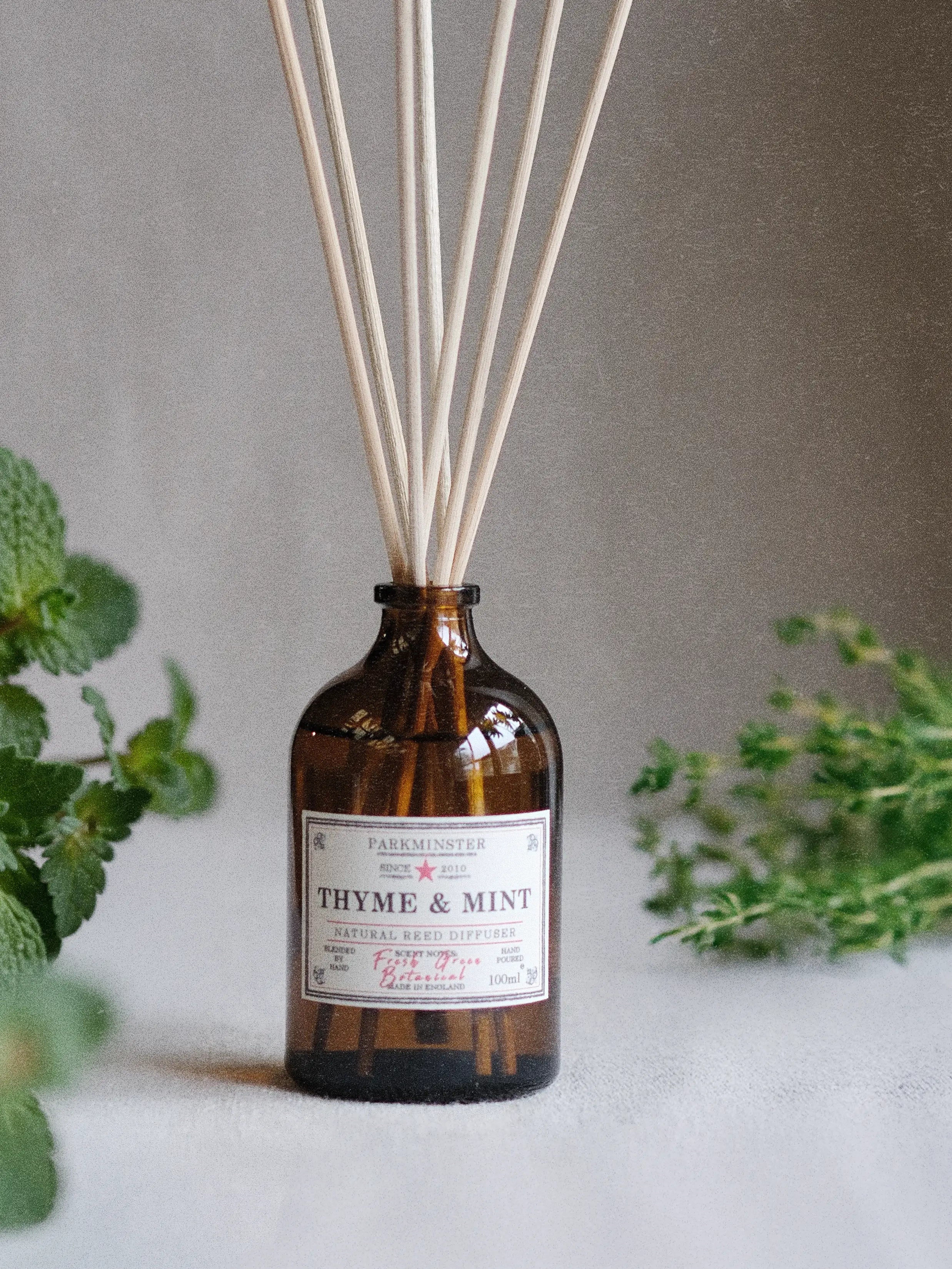 a natural Thyme and Mint reed diffuser with fresh herbal scent, plant based home fragrance in amber glass bottle
